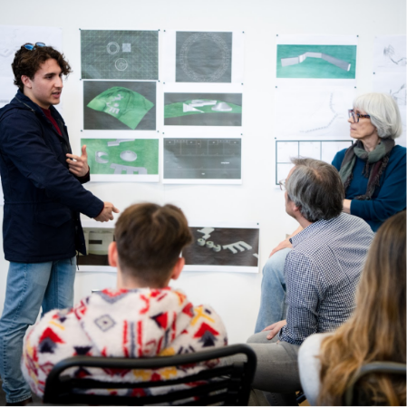 A person presenting architectural or design plans to an audience, with various images and diagrams